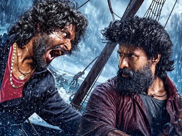 Soori in a dramatic pose from the Mandaadi film poster, standing on a boat against a stormy sea backdrop