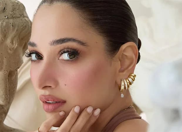 Tamannaah Bhatia posing with Joy Personal Care lotion bottles for campaign