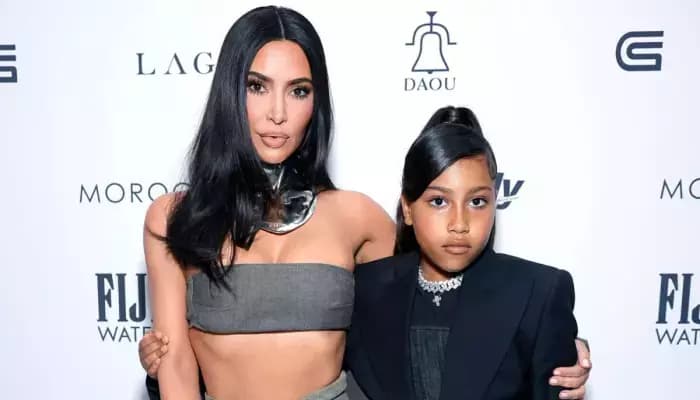 Kim Kardashian with her daughter North West, both styled in bold, edgy looks with blue hair and accessories.