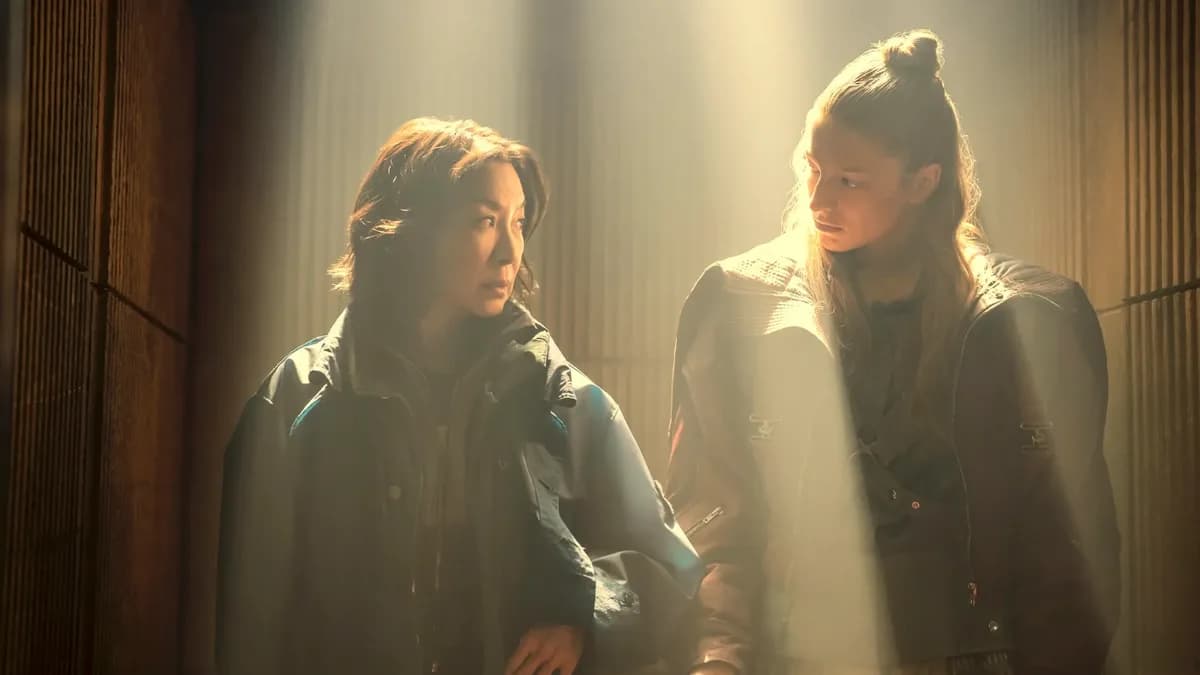 Michelle Yeoh as Olwen, a replicant nearing the end of her life, standing in a rain-soaked LA street, eyes fixed ahead. Hunter Schafer as Cora, face half-shadowed, looks back with tension.