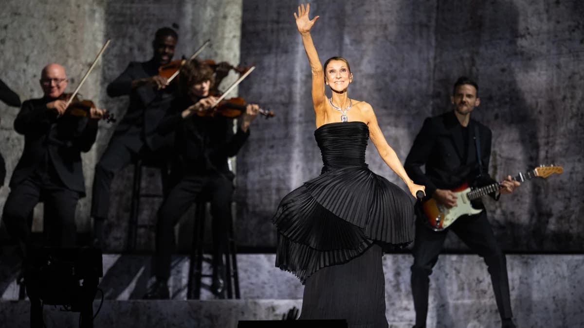 Céline Dion performing on stage in a black strapless gown during her Paris residency opening night