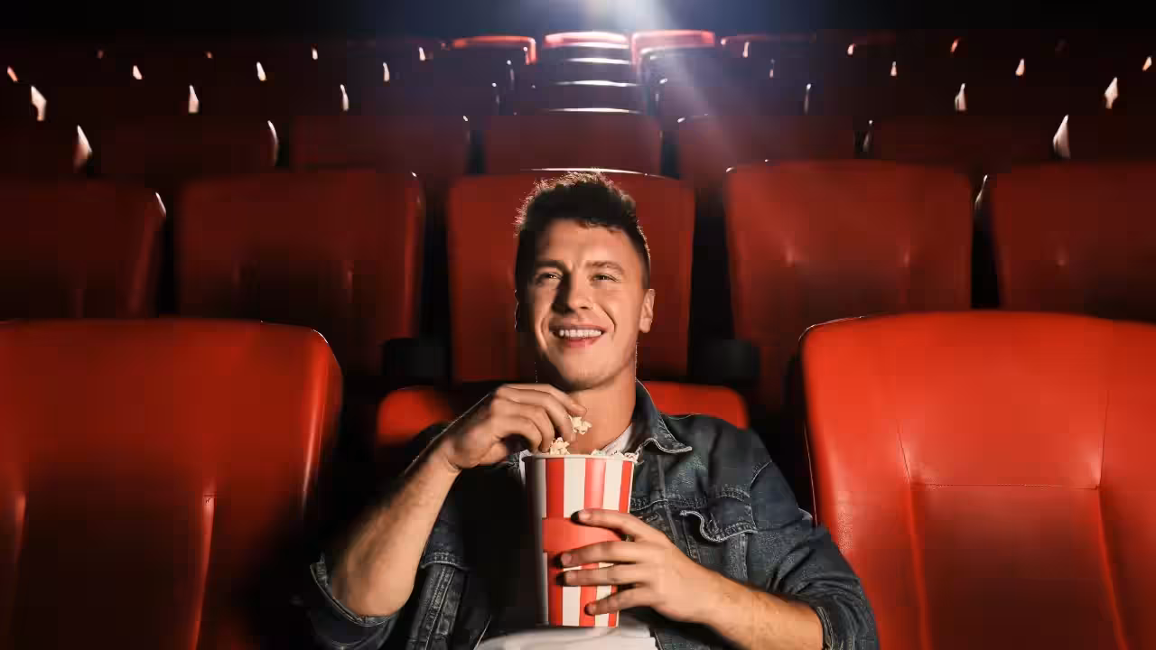 A dimly lit cinema hall with a single phone screen glowing in the darkness