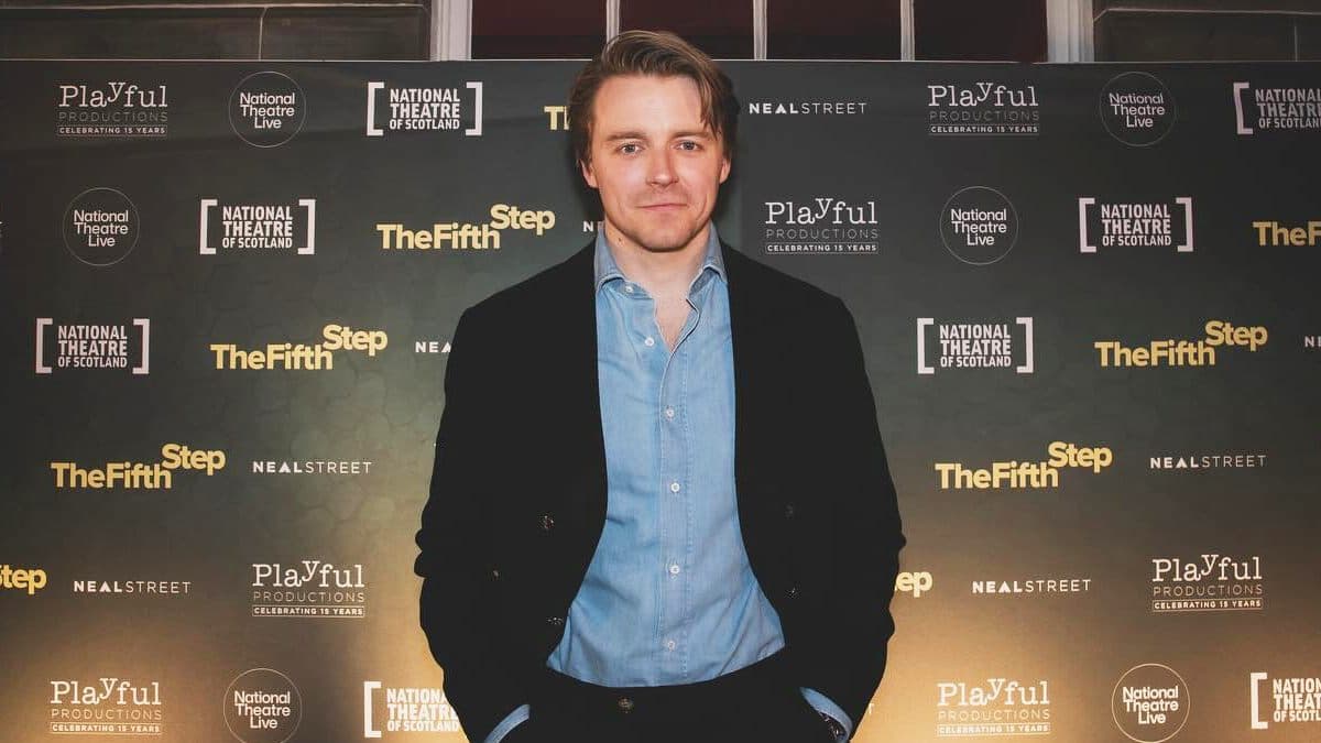 Jack Lowden at a red carpet event in a dark suit