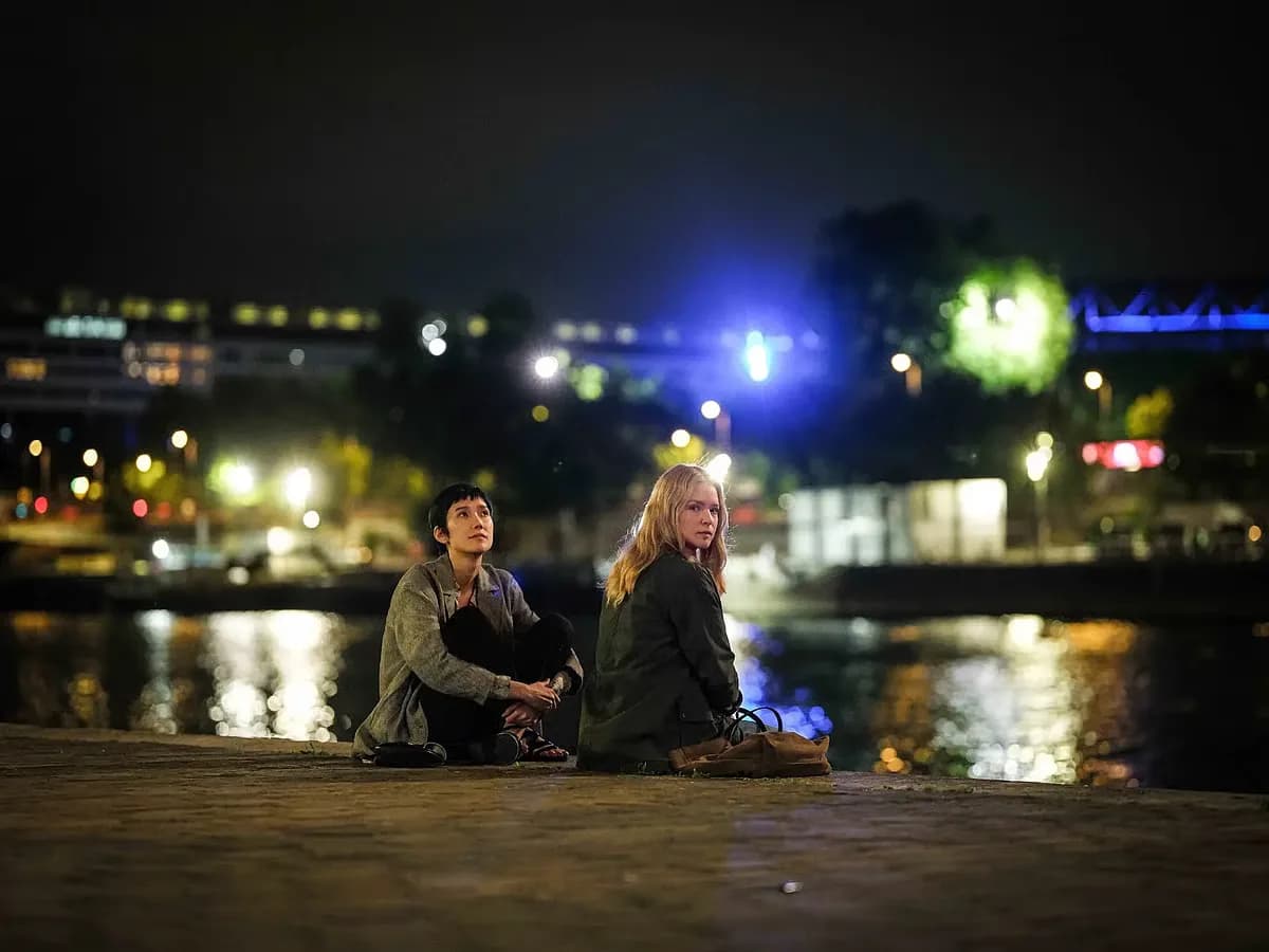 A still from All of a Sudden showing Virginie Efira and Tao Okamoto sitting together in a nursing home, looking thoughtful under soft light.