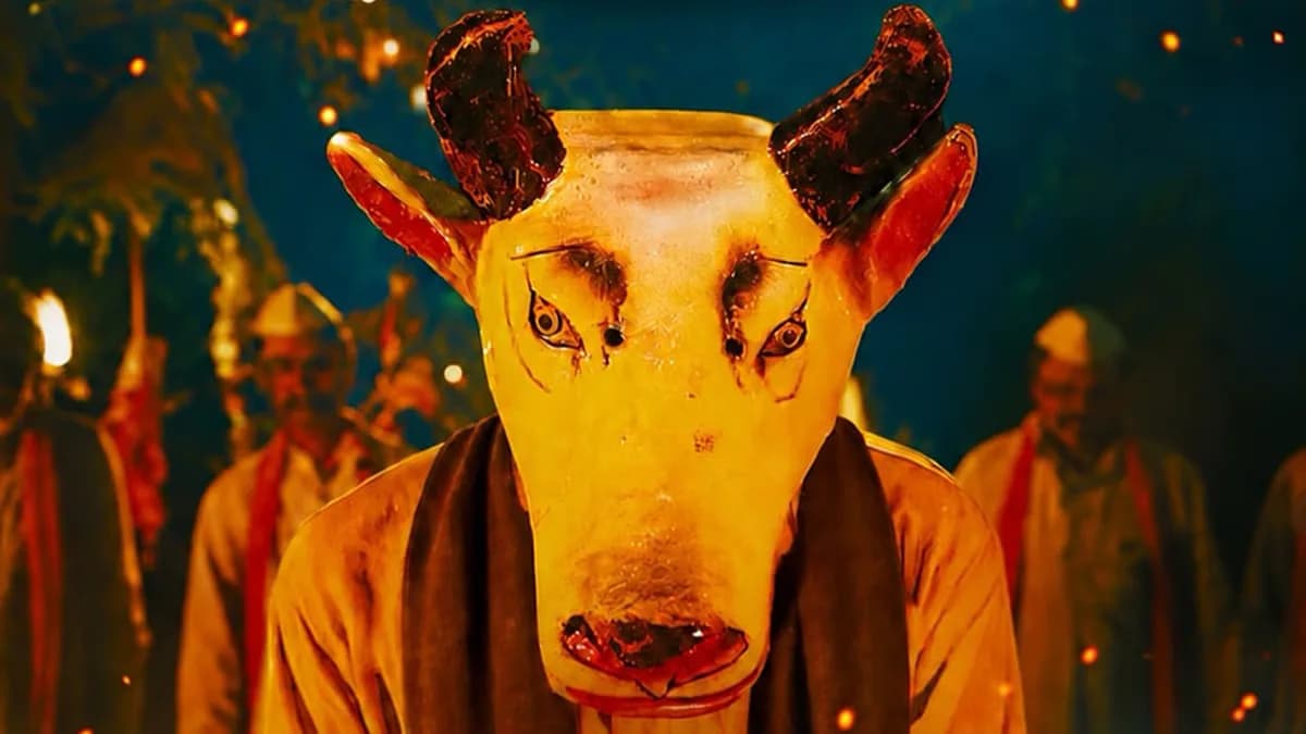 A still from Gondhal showing Kishor Kadam in a rural setting, eyes intense, standing amidst traditional village architecture.