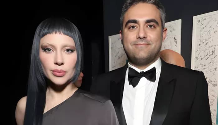 Lady Gaga walking outdoors while holding an infant close to her chest