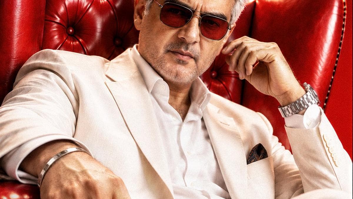 Ajith Kumar seated in a red leather wingback chair wearing a white suit and red-tinted sunglasses, holding a dice game piece, in the first look poster for Dare Devil.