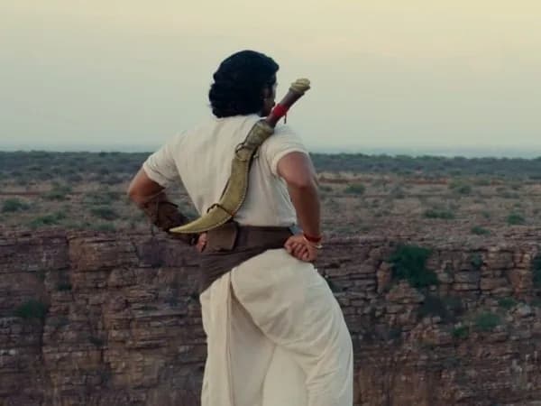 Vijay Deverakonda in a historical warrior costume, standing on a hill under a stormy sky