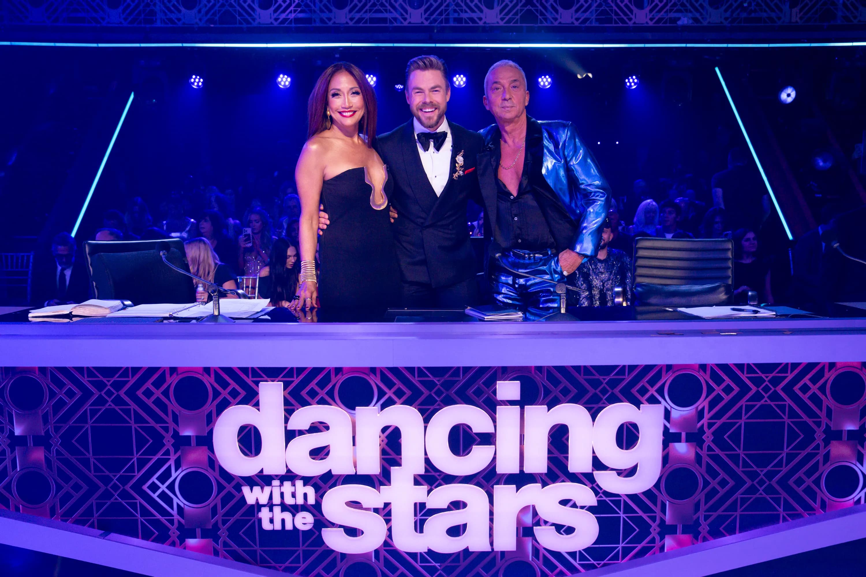 A glittering ballroom stage set for Dancing with the Stars, with dancers in costume under bright studio lights.