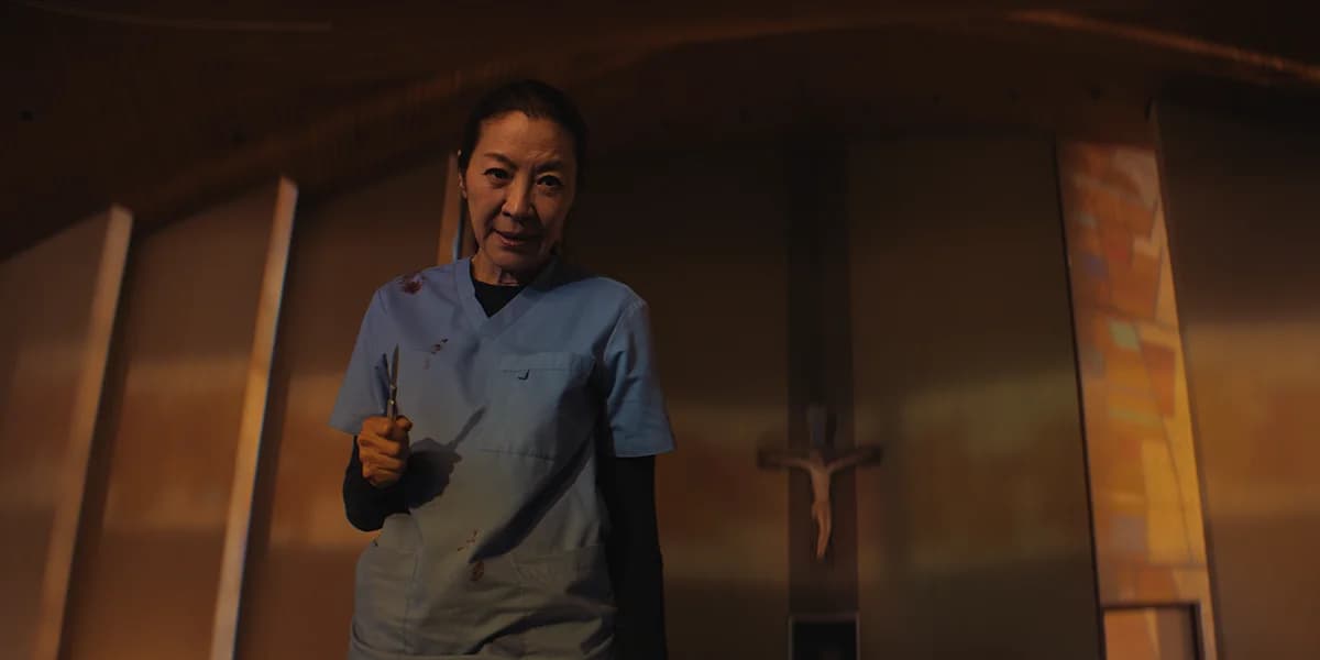 Michelle Yeoh in a still from The Surgeon, standing in surgical scrubs holding a scalpel
