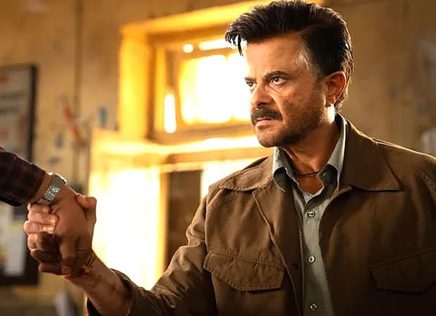 Anil Kapoor in a military-style jacket, standing in front of a rural village backdrop, looking determined.