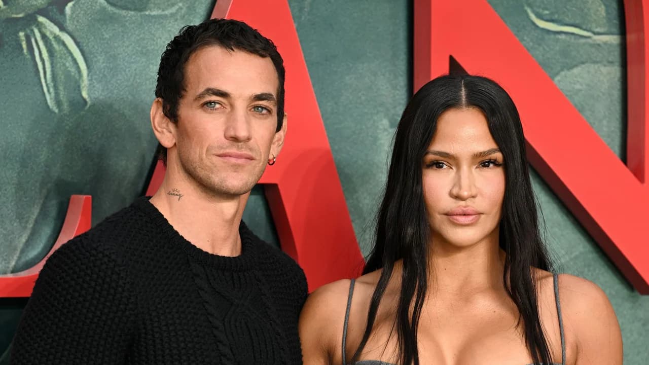 Cassie in a gray dress standing arm in arm with husband Alex Fine in a black outfit at the MobLand season two premiere in London.