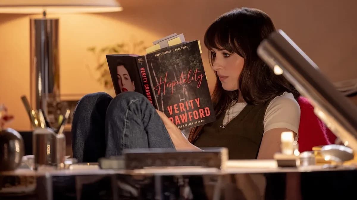 Anne Hathaway and Dakota Johnson in a tense scene from Verity, standing in a dimly lit hallway.