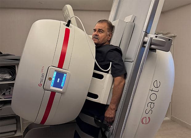 Sharat Saxena standing during an MRI scan session with visible discomfort on his face.