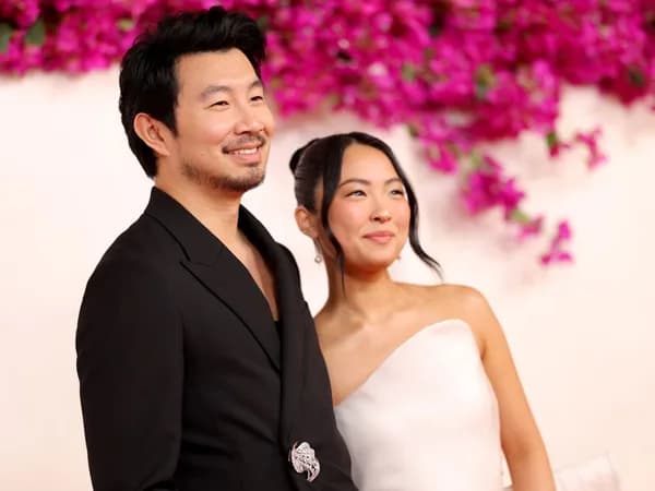 Simu Liu and Allison Hsu smiling at a private wedding ceremony in France, surrounded by autumn foliage.