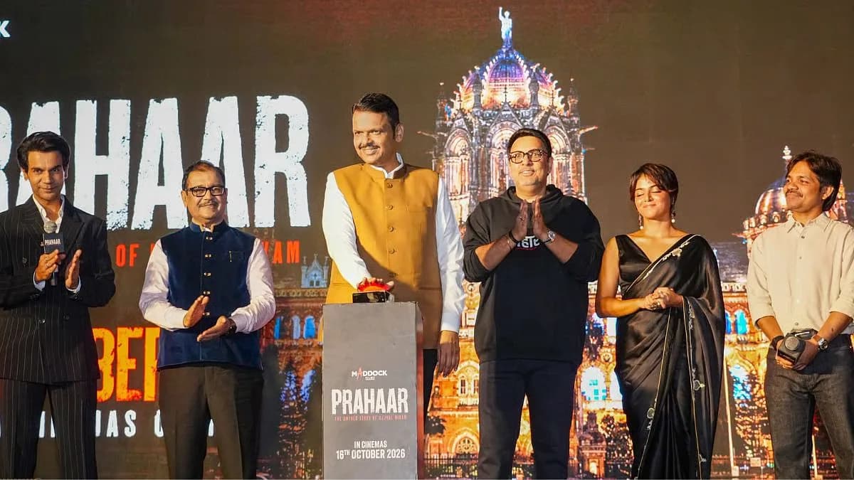 Chief Minister Devendra Fadnavis speaking at the Prahaar trailer launch at Mumbai CSMT, with Rajkummar Rao visible among the audience.