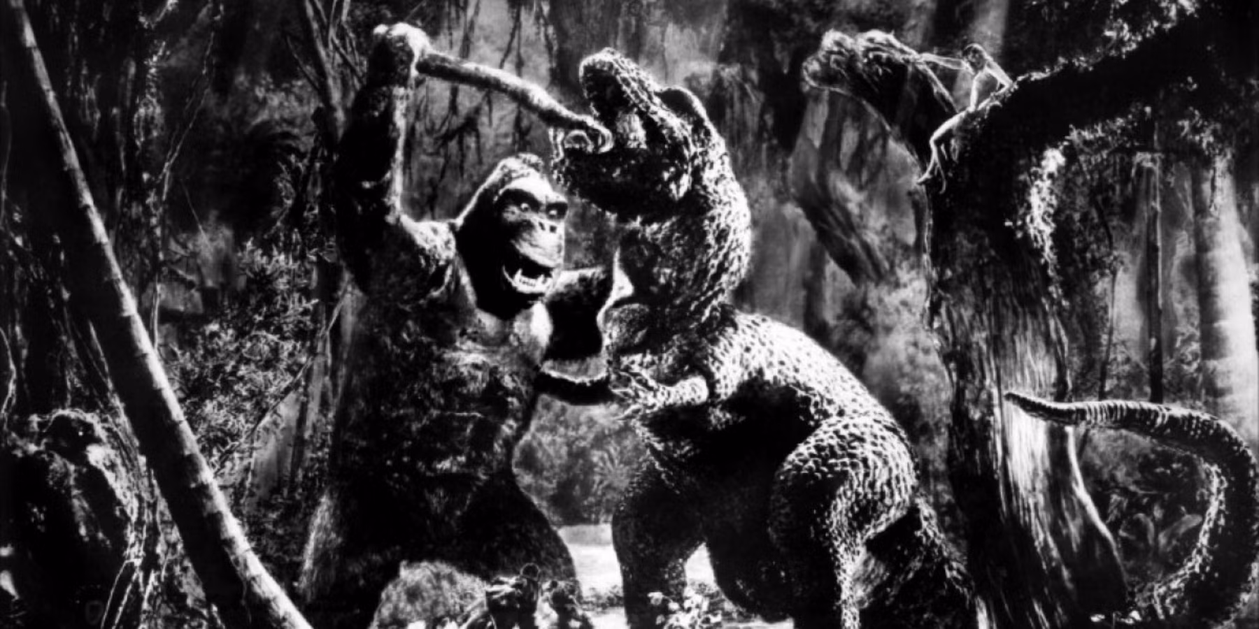 A black-and-white still from the 1954 Godzilla film showing the creature emerging from the sea, silhouetted against a stormy sky.