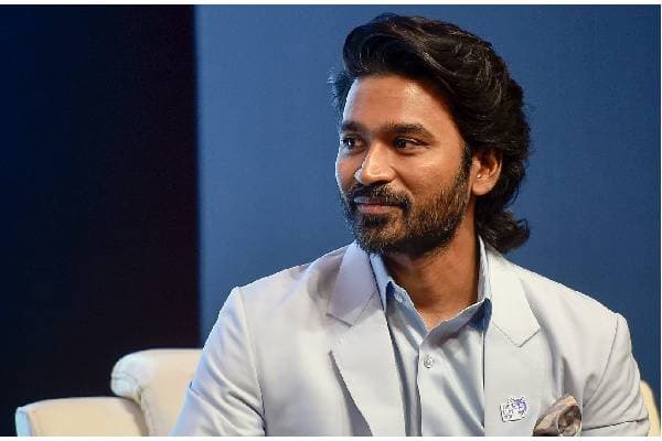 Tamil actor Dhanush at a public event, smiling and dressed casually