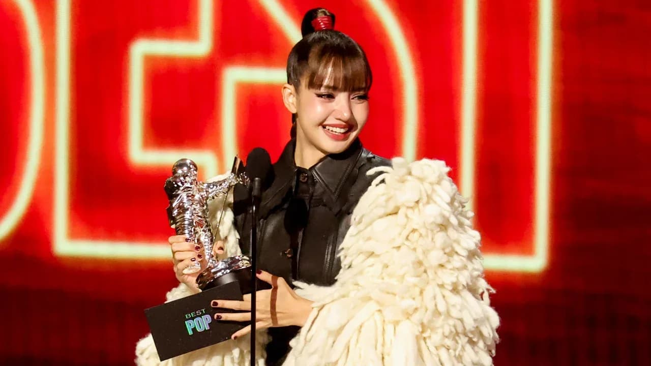 Lisa on stage at the 2026 MTV VMAs holding her Best Pop Moonman trophy after her win.