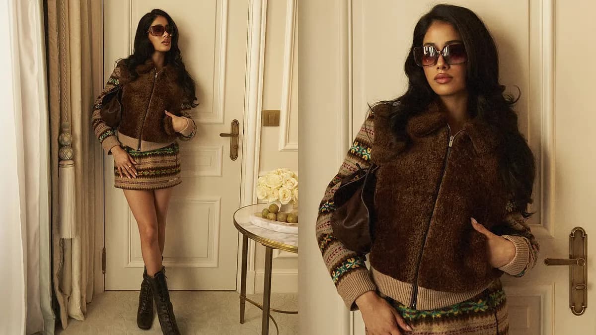 Janhvi Kapoor in a fitted blue knit top, matching multi-toned mini skirt, cropped brown jacket, and tall black lace-up boots at Miu Miu's Paris Fashion Week show.