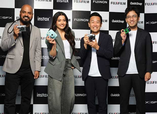 Rashmika Mandanna posing with Fujifilm instax camera, smiling at the camera