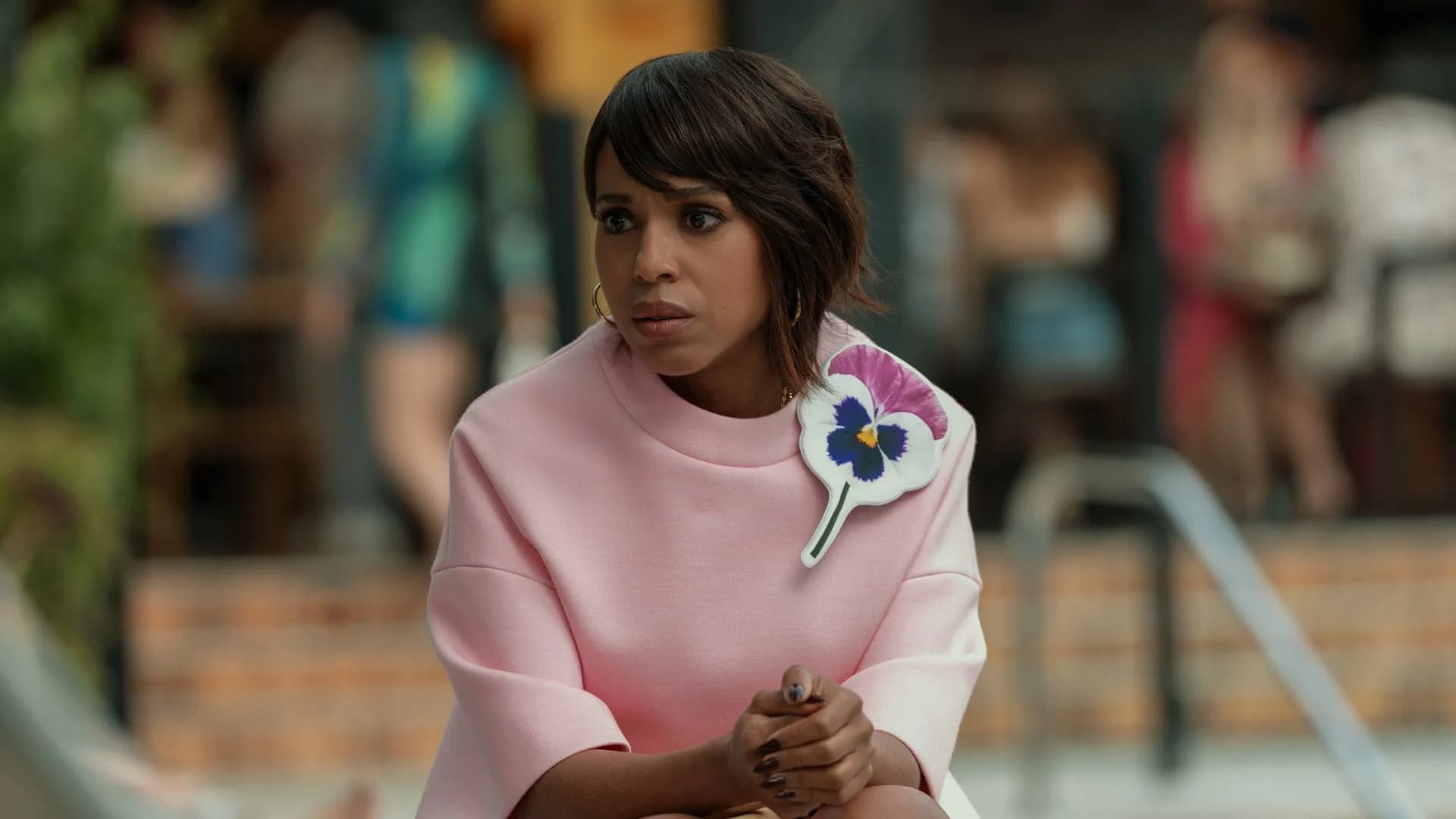 Kerry Washington in a dramatic pose, standing on a cliff overlooking the sea, wearing a dark coat. The sky is stormy.