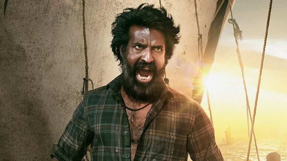 Soori as Kaali, standing on a wooden boat in rough waters, face set against the stormy sky.