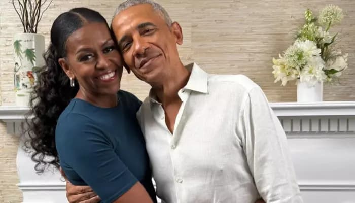 Barack and Michelle Obama smiling together, holding hands, in a warm embrace during a private moment captured on camera.