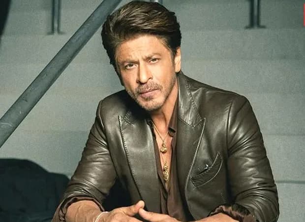 Shah Rukh Khan smiling at a public event, dressed in formal attire