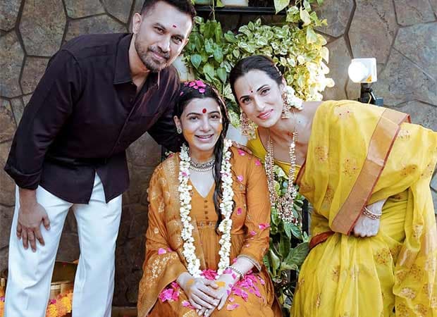 Samantha Ruth Prabhu in a mustard and gold outfit with fresh flowers in her hair, seated beside Raj Nidimoru during her Seemantham ceremony.