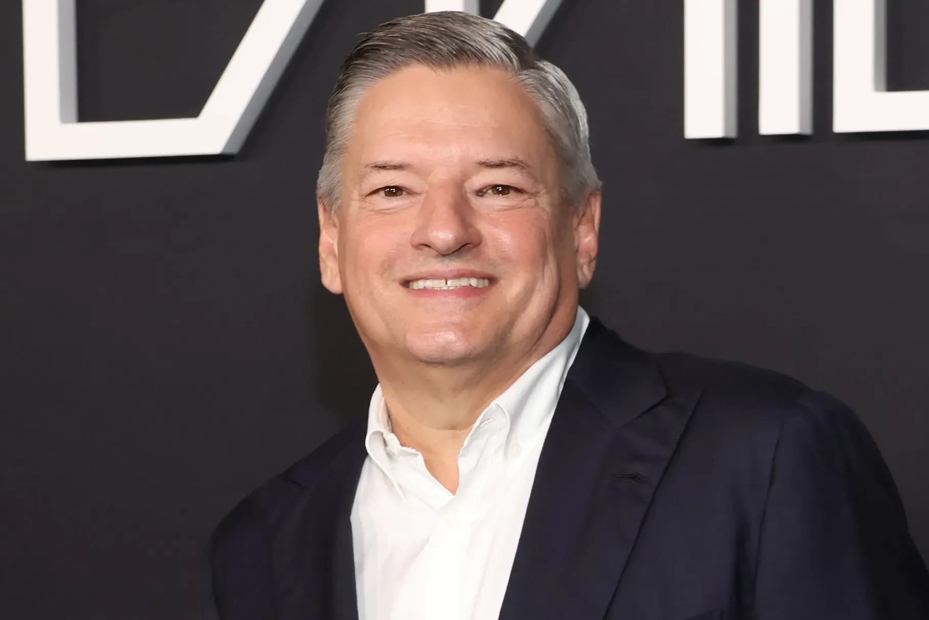 Ted Sarandos speaking at Bloomberg Screentime conference with Netflix branding in the background