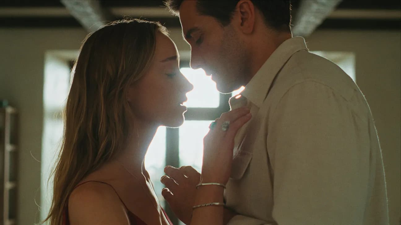Jake Gyllenhaal and Phoebe Dynevor in a promotional still from the Remain teaser trailer, standing close together in a coastal home interior.