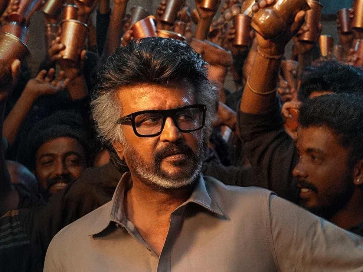 Rajinikanth in a black suit, standing in front of a cinematic backdrop with 'Jailer 2' in bold red letters.