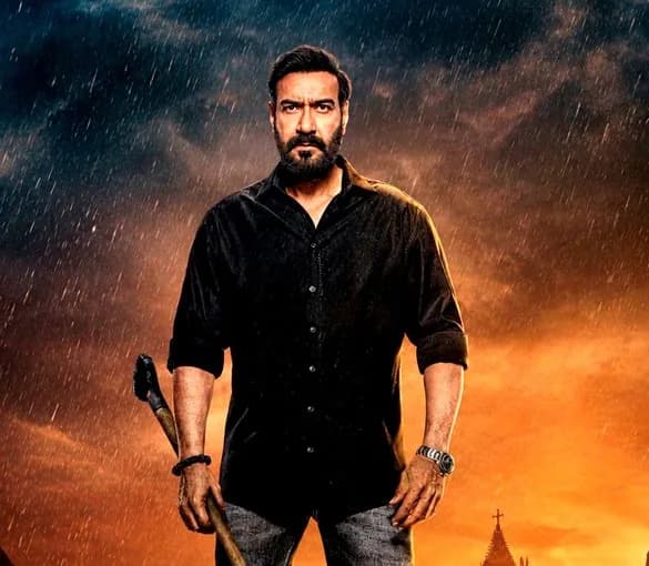 Ajay Devgn in a tense scene from Drishyam: The Conclusion, standing against a dark background with a determined expression.
