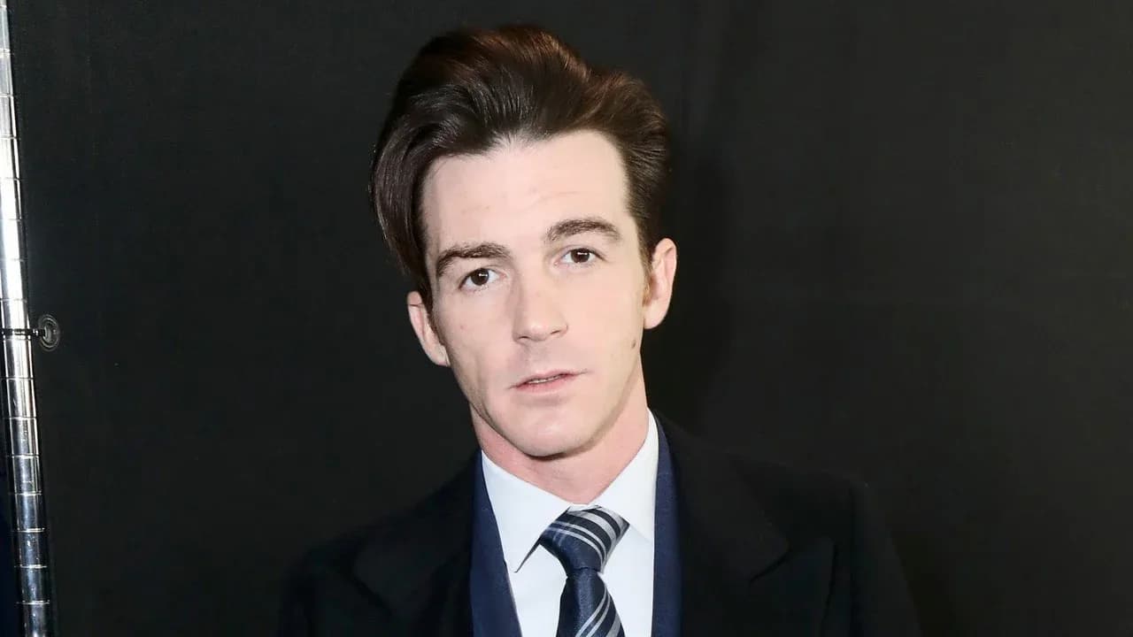 Drake Bell speaking into a phone, looking frustrated, with a SAG-AFTRA health plan website screenshot visible in the background.