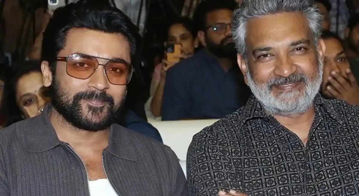 SS Rajamouli speaking on stage at the Don't Trouble the Trouble promotional event in Chennai with Suriya seated in the front row