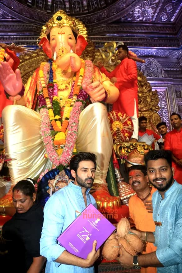 Kartik Aaryan kneeling before Lalbaugcha Raja, holding his National Film Award at the deity's feet