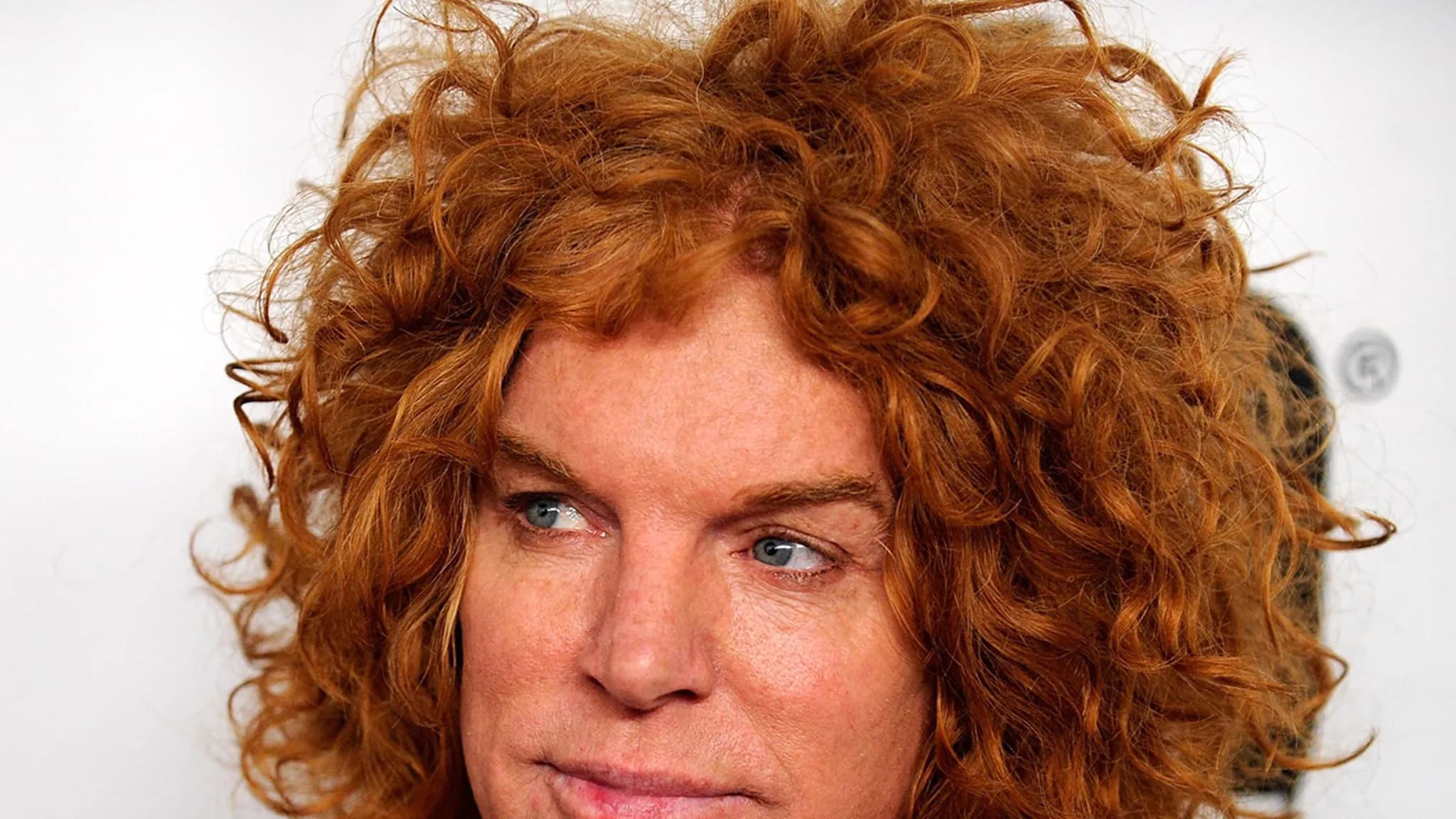 Carrot Top lying in a hospital bed with family members holding his hand, a hospital monitor beeping softly in the background.