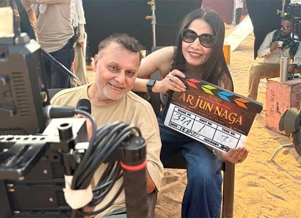 Celina Jaitly standing on set, holding a small idol of Mumba Devi, smiling at the camera
