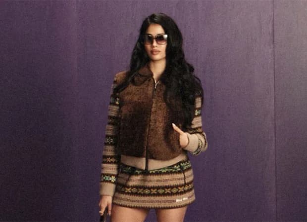 Janhvi Kapoor in a brown textured jacket and colorful knit skirt, oversized sunglasses, standing confidently at Miu Miu Paris Fashion Week.