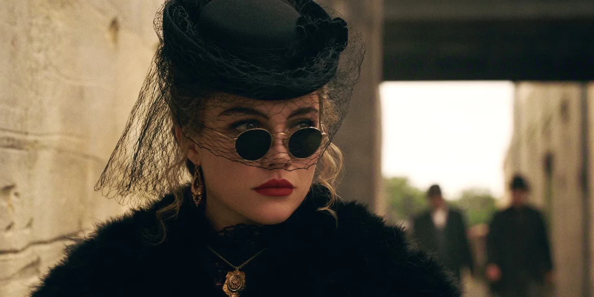 Florence Pugh in a Western hat, standing on a dusty ridge under a wide sky.