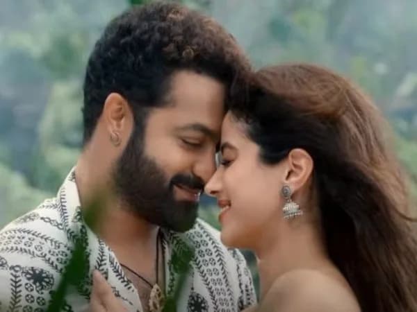 Jr NTR speaking into a microphone at a press event, face tense, eyes sharp.