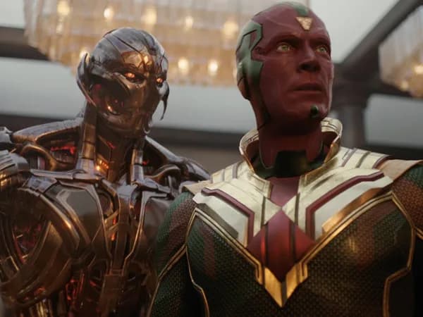 Trailer still of Paul Bettany as White Vision standing in a digital void, surrounded by flickering AI avatars, with James Spader's Ultron looming in shadow.