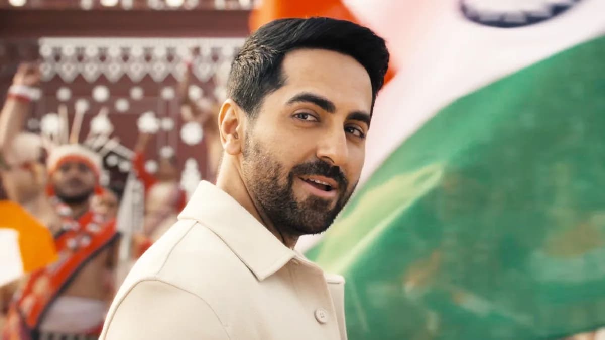 Ayushmann Khurrana in a military-style outfit, standing in front of a red-white-blue backdrop, mid-chorus of 'Jai Hind'