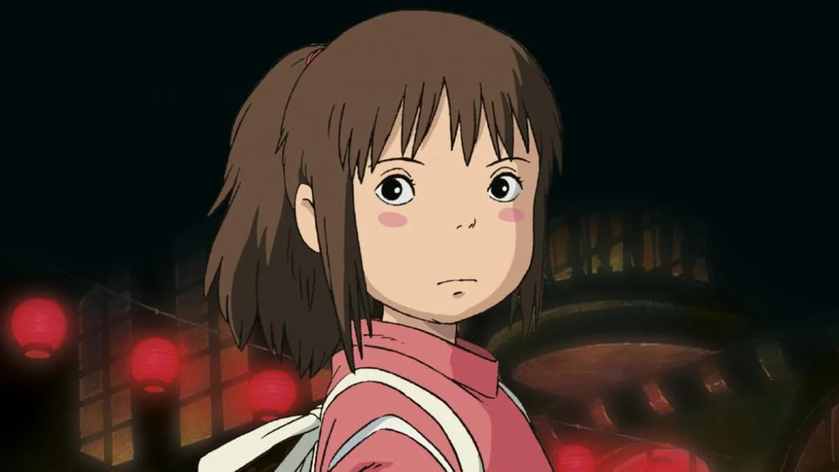 A still from Spirited Away showing Chihiro walking through a forest with a glowing lantern, surrounded by spirits.