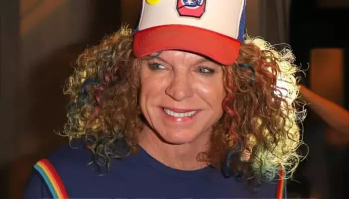 Carrot Top performing on stage in his signature colorful, patchwork outfit