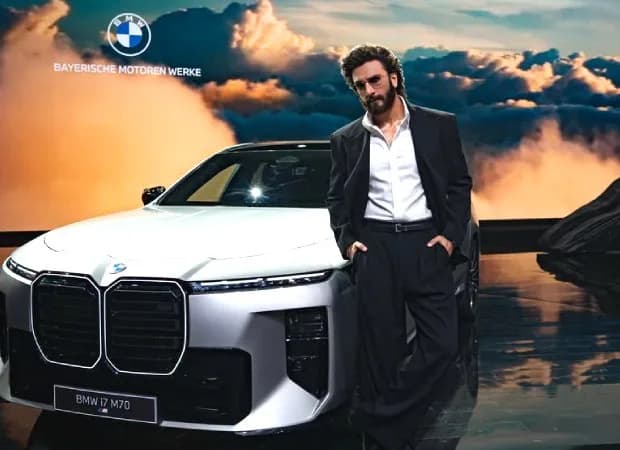 Ranveer Singh standing beside a sleek black BMW i7 at a launch event