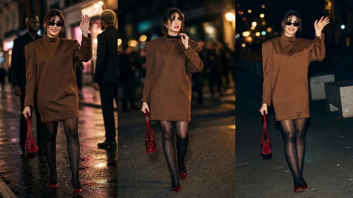 Nora Fatehi in a chocolate-brown mini dress with wide shoulders, cherry-red heels, and a patent-leather handbag at Louboutin's Paris Fashion Week show