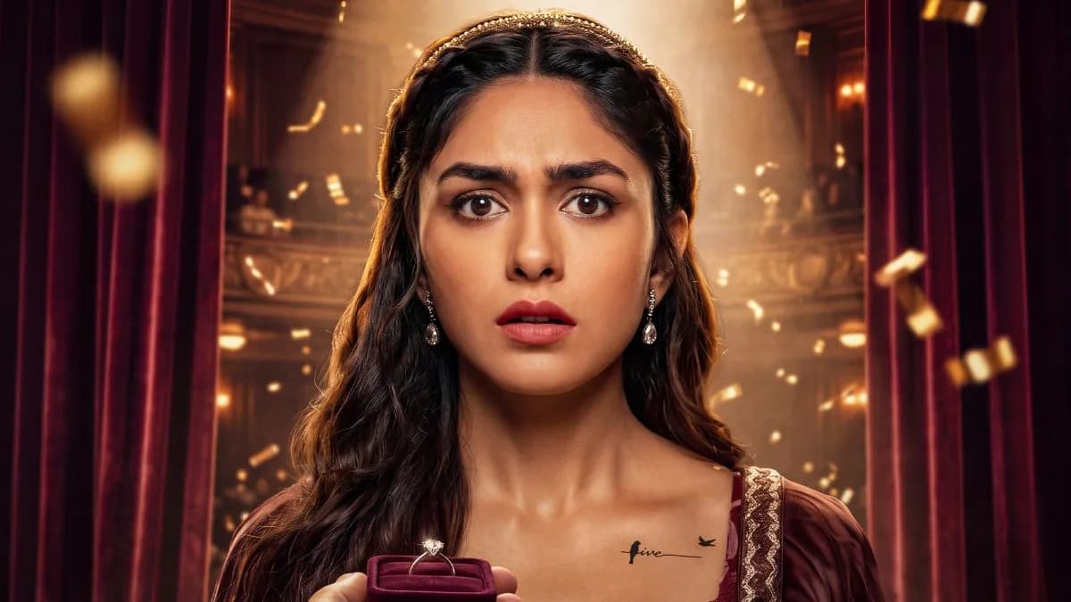 Mrunal Thakur in a dramatic pose, looking conflicted, against a dimly lit stage backdrop