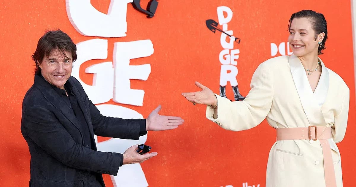 Tom Cruise in heavy prosthetic makeup standing on the Los Angeles red carpet with Emma D'Arcy and Jesse Plemons